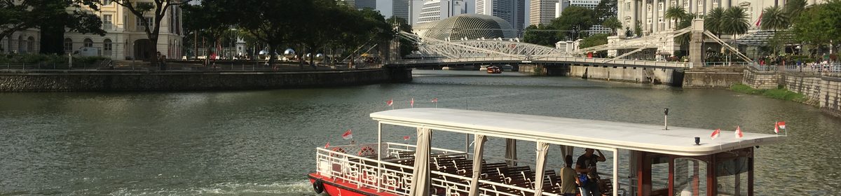 A bumboat water taxi on the Singapore River with the city skyline behind